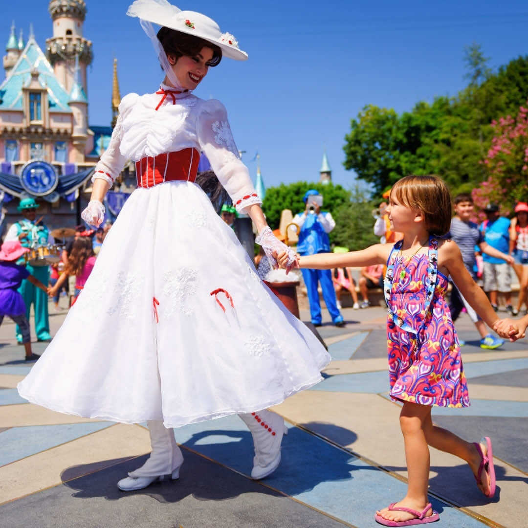 An actress playing Mary Poppins at Disneyland® Resort leads a young girl by the hand.