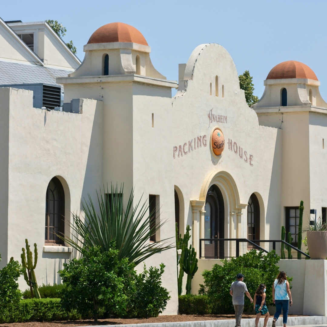 A side view of the Anaheim Packing House building, with a family walking in front of it.