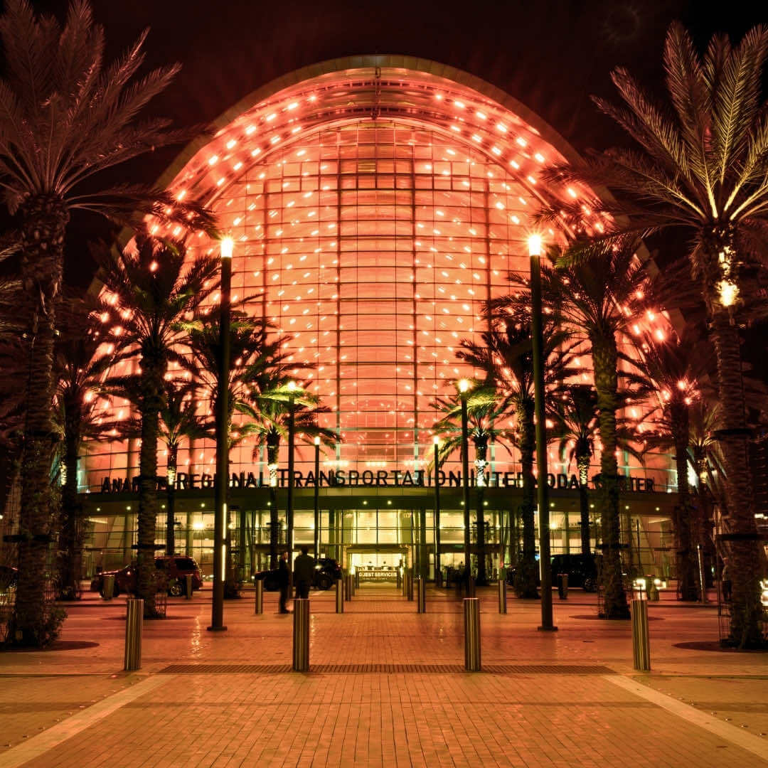 A front view of the Anaheim Regional Transportation Intermodal Center (ARTIC) illuminated with an orange glow at night.